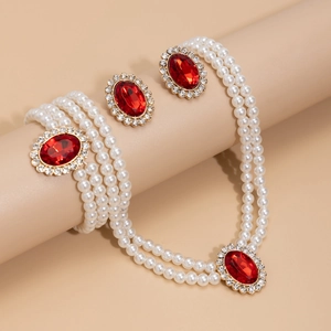 Detail of vintage jewelry set with red oval gems, pearls, and crystals on gold base
