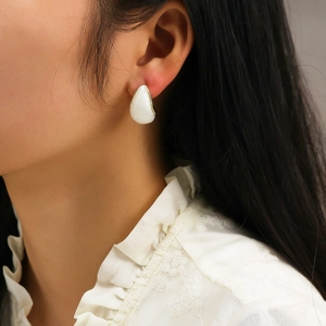Close-up of gold-plated square hoop earring with white resin inlay on female model