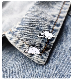Macro shot of cute sheep and cartoon pins on denim jacket showing fine enamel details