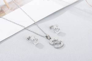 Detail view of silver necklace and earrings set featuring 'SMILE' crystal letter pendants