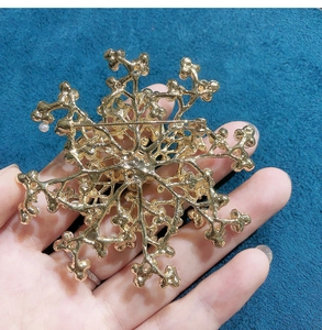 Close-up of golden coral snowflake brooch back view with safety pin mechanism