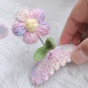 Detail of handmade crochet puff flower hair clip with pink yarn and sparkling glitter accents