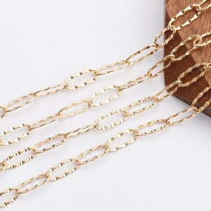 Close-up of 18K gold plated oval wave link chain draped over a dark wood display block