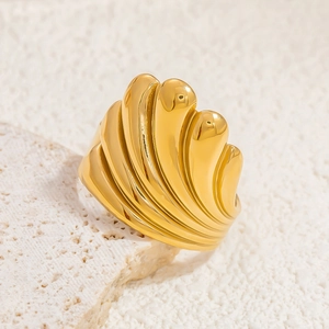 Macro view of gold 18k stainless steel ring with striped shell texture on coral background