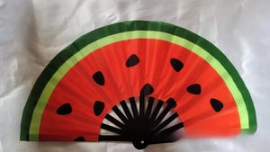 Macro detail of watermelon printed folding fan with red gradient and black bamboo ribs