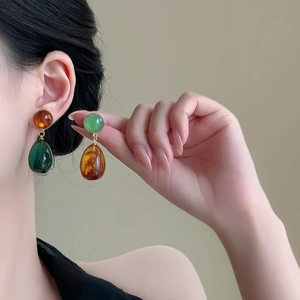 Asymmetric resin teardrop earrings in amber and emerald green with gold accents