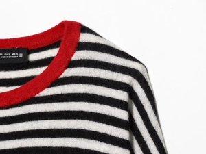 Detail of striped knit sweater with red crew neck collar and size label closeup