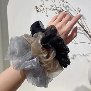 Large oversized organza scrunchies in black, gold and silver on model's wrist