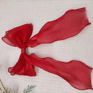 Close-up of a large red organza ribbon bow hair clip with long flowing streamers