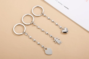 Detail of silver stainless steel keychains with heart and girl silhouette charms