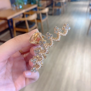 Detailed view of a golden wave hair claw clip with elegant pearls and sparkling rhinestones