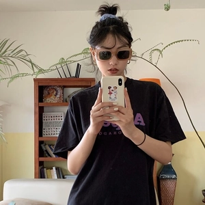 Gros plan sur des lunettes de soleil carrées caramel rétro et un t-shirt noir