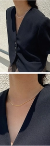 Detail of minimalist 925 sterling silver cross pendant and gold flat chain on model