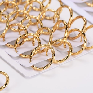 Minimalist twisted gold stainless steel hoop earrings displayed in bulk on white cards