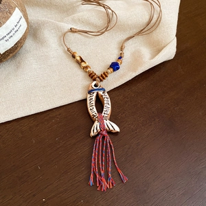 Detailed view of a ceramic fish pendant with ethnic tassels and colorful wooden beads