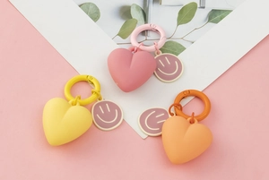 Close-up of heart-shaped keychains in pink, yellow, and orange with purple smiley charms