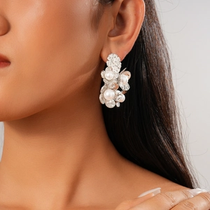 Detail view of flower petal earrings with textured silver metal and white pearls on a model