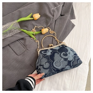 Detailed view of denim kiss-lock bag with auspicious cloud print and gold chain strap