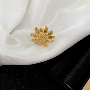 Macro detail of golden daisy ring with textured petals on white silk and dark background