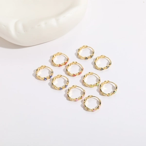 Detailed top view of eleven gold evil eye hoop earrings in various enamel colors on white