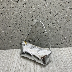 Macro detail of silver woven leather texture and gold zipper on a chic square bag