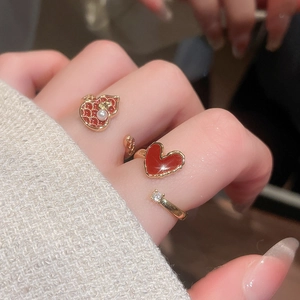 Detail of red enamel heart ring with pearls and gold band on a model hand