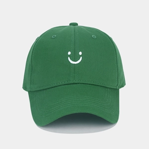 Close-up of a dark green baseball cap with white embroidered smiley face and curved brim