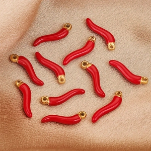 Red enamel chili pepper pendants with gold-plated loops on soft fabric for jewelry making