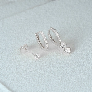Macro shot of silver earring set featuring triple diamond accents and hoop designs