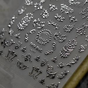 Close-up of silver laser embossed nail art stickers with metallic texture and patterns