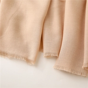 Detalle macro de bufanda beige de tela rugosa con textura suave y bordes de flecos