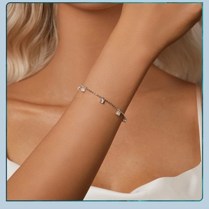 Detailed close-up of a delicate silver chain bracelet with square clear zircon stones on a wrist