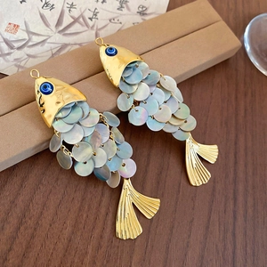 Detailed close-up of fish-shaped hair clip with iridescent shells and evil eye detail