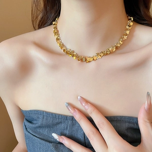 Dettaglio ravvicinato di un girocollo con paillettes a cuore dorate su una modella