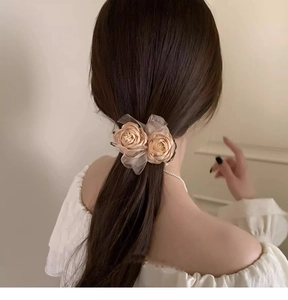 Detail of beige lace flower hair claw clip securing a bun on a woman's dark hair