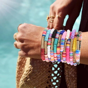 Colorful Heishi beaded friendship bracelets stacked on wrist with summer beach vibe
