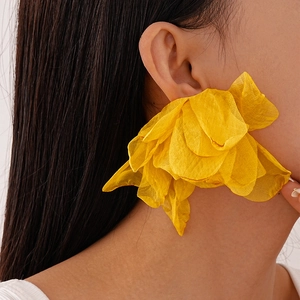 Close-up of a large yellow fabric flower earring with layered tulle petals for a vacation look