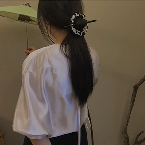 Detailed view of a Chinese mother-of-pearl hair pin styled on a woman's bun hairstyle