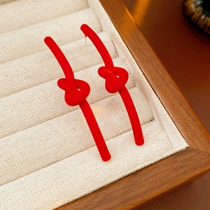 Macro shot of red matte knotted stud earrings placed in a wooden jewelry box