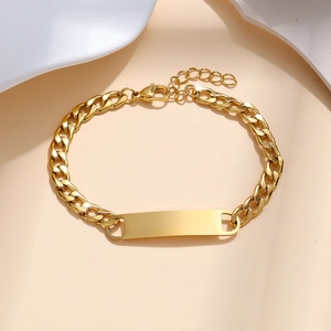Macro view of gold stainless steel Cuban chain bracelet with blank rectangular ID plate