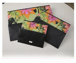 Flat view of foldable floral gift bags with gold woven handles and portable storage design