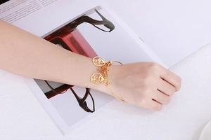 Detail of 18k gold plated bracelet featuring hollow boy, girl and heart shaped charms
