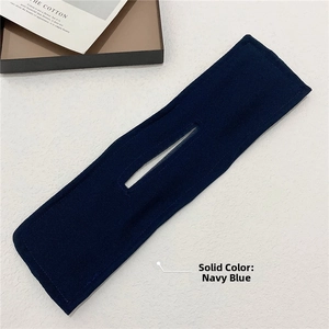 Macro shot of navy blue fabric deft bun maker hair tool on a white marble background