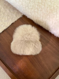Détail d'une pince à cheveux en peluche beige avec texture douce sur support en bois
