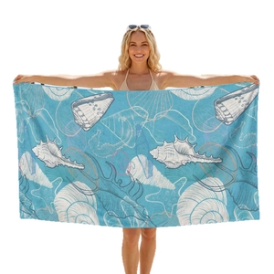 Microfiber beach towel with sea shell print held by a smiling model for size display