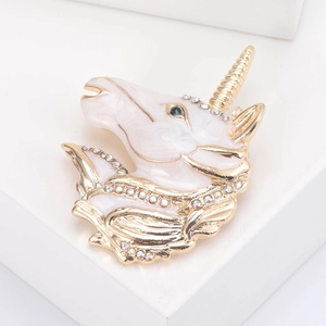 Macro shot of unicorn brooch with gold trim white enamel and sparkling rhinestones
