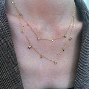 Detail of layered gold titanium necklace featuring geometric pendants with clear zircon