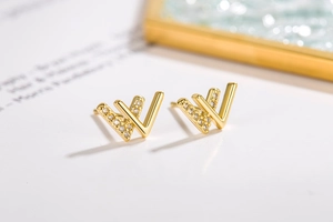Macro shot of gold V-shaped stud earrings featuring sparkling cubic zirconia stones