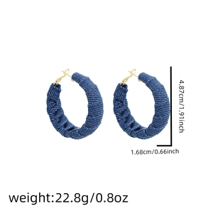 Detailed view of large blue denim hoop earrings with white dots and size measurements