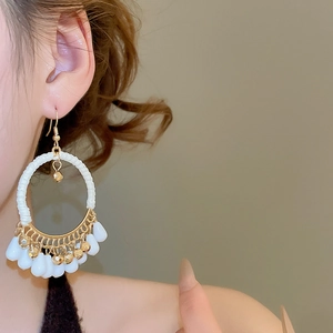 Detailed shot of Bohemian hoop earrings with white cord wrap and gold fan teardrop beads